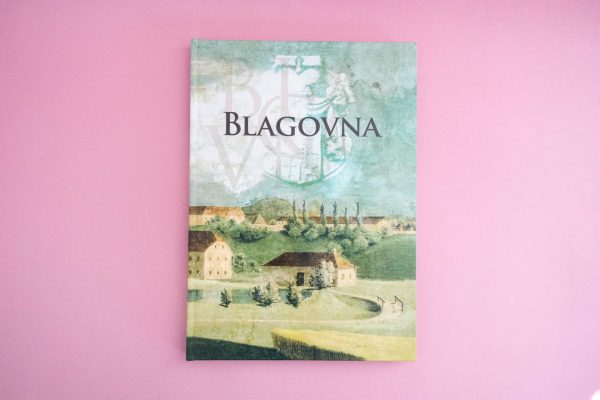 Blagovna je knjiga z naslovnico s podeželskim prizorom zgodovinskih stavb, dreves in polj na enobarvnem rožnatem ozadju.