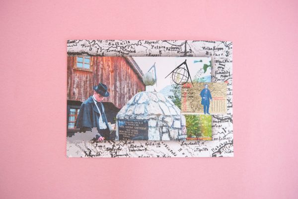 Blaž Kocen - Maksimum karta (razglednica) počiva na rožnati površini, ki jo krasijo starinski potovalni motivi, ročno napisani zapiski in žig, ki prikazuje osebo v klobuku ob kamnitem spomeniku.