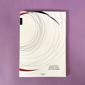 Knjiga z naslovom "Josip Ipavec, Izbrane pesmi/Selected songs" (Josip Ipavec, Izbrane pesmi) z belo platnico s tankimi črnimi in rdečimi ukrivljenimi črtami je postavljena na vijolično površino.