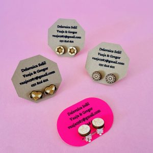 Trije pari Leseni uhani so prikazani v rožnati barvi z vzorci zvezd, srca in kroga. Vsak par je nameščen na kartici - dva rjava, eden roza - z vidnimi kontaktnimi podatki.
