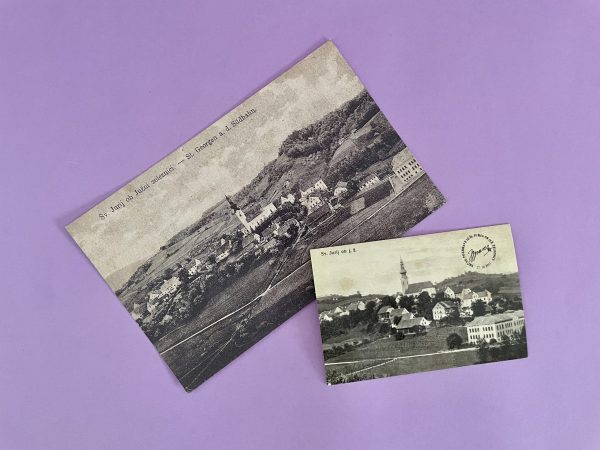 Dve starinski črno-beli fotografiji "Arhivska razglednica Sv. Jurij ob Južni železnici", ki prikazujeta mestece in cerkev, sta postavljeni pod kotom na pastelno vijolično ozadje in se rahlo prekrivata.