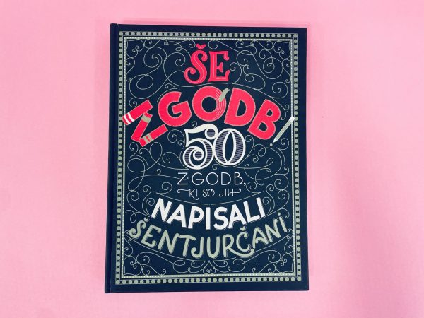 Knjiga "ŠE ZGODB! 50 zgodb, ki so jih napisali Šentjurčani" ima okrasno črno platnico s slovenskim besedilom v rdeči, beli in zlati barvi ter je prikazana na rožnati podlagi.