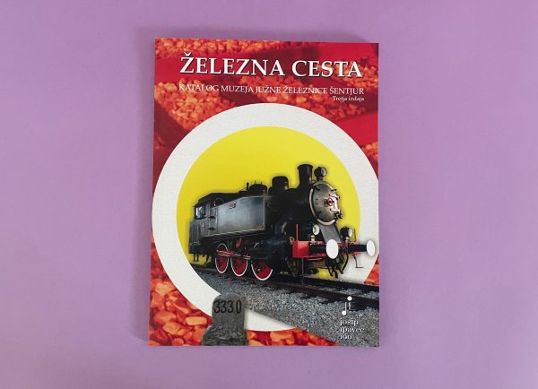 Železna cesta je knjiga s parno lokomotivo na naslovnici, ki je postavljena na svetlo rumeno-belo krožno ozadje z vijolično barvo pod njim.